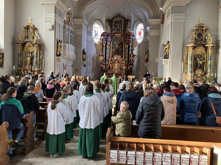 Man sieht eine volle Kirche und die Ministranten von hinten